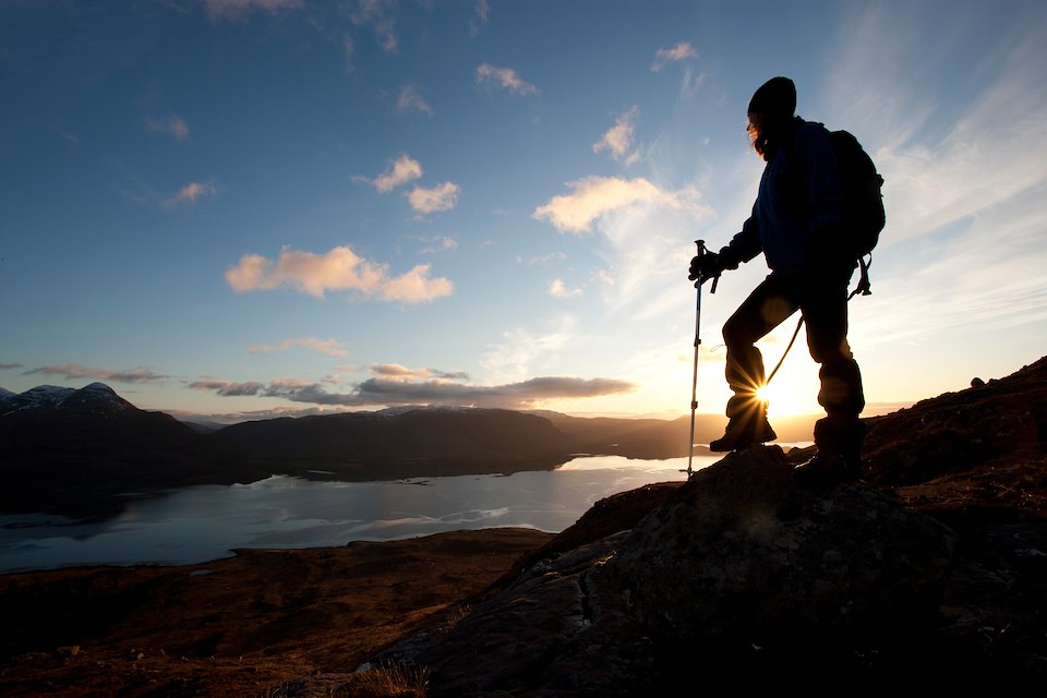 Walker silhouetted at sunset overlooking Upper Loch Torridon, Beinn Alligin, Torridon, Scotland