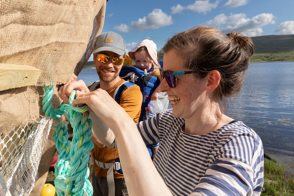 Jessica Spence adding securing rope to black-throated diver nesting platform, Overscaig, Sutherland